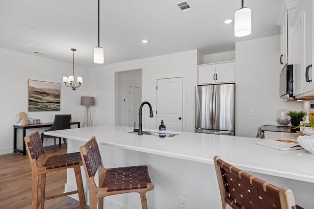 6051 Mill Tree Ct, Nashville, TN 37221 - kitchen featuring appliances with stainless steel finishes, light wood-type flooring, a breakfast bar, white cabinetry, and light countertops