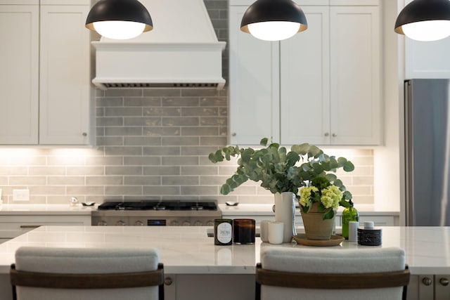 7019 Bolton St, Franklin, TN 37064 - kitchen with stainless steel appliances, exhaust hood, tasteful backsplash, light stone counters, and white cabinets