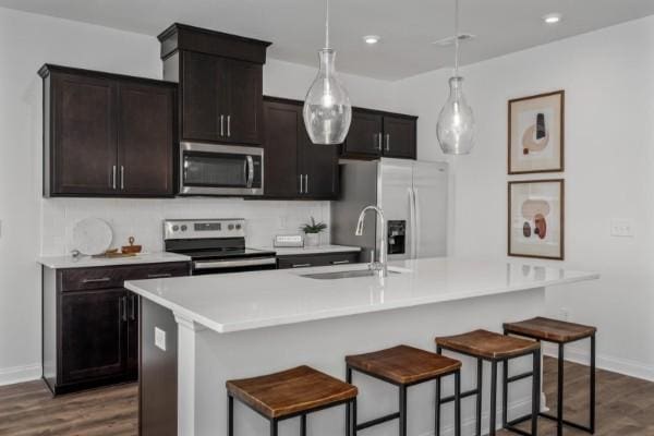 2202 Melk Ln, Columbia, TN 38401 - kitchen featuring appliances with stainless steel finishes, a breakfast bar area, dark wood finished floors, light countertops, and hanging light fixtures