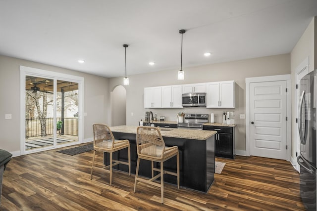 2015 Morgan Ct, Springfield, TN 37172 - kitchen featuring stainless steel appliances, arched walkways, dark wood finished floors, a center island with sink, and a breakfast bar area