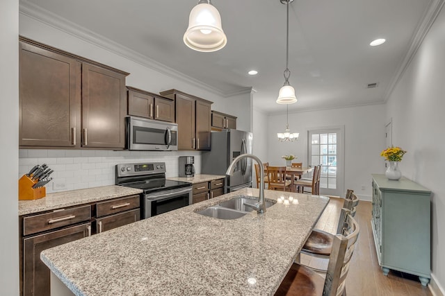4029 Viola Ln, Franklin, TN 37069 - kitchen with stainless steel appliances, an island with sink, dark brown cabinetry, light wood finished floors, and decorative backsplash