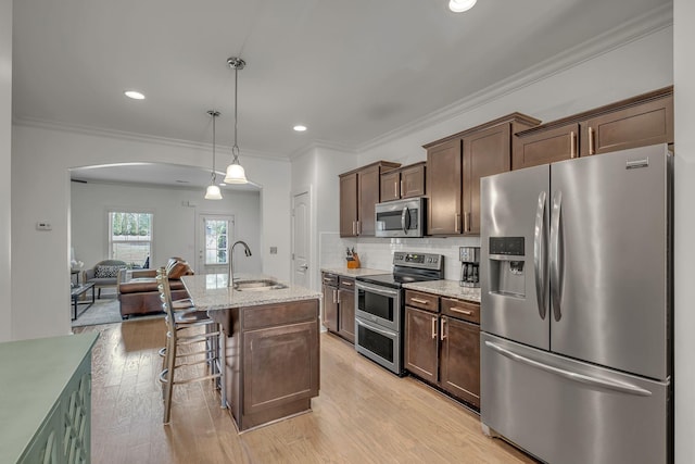4029 Viola Ln, Franklin, TN 37069 - kitchen with appliances with stainless steel finishes, arched walkways, light wood-style floors, light stone countertops, and dark brown cabinets