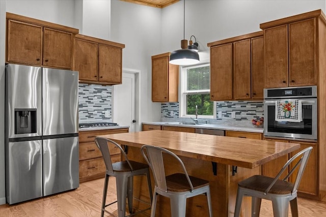 2006 Goodrich Rd, Nunnelly, TN 37137 - kitchen with stainless steel appliances, a high ceiling, tasteful backsplash, light wood-type flooring, and brown cabinets