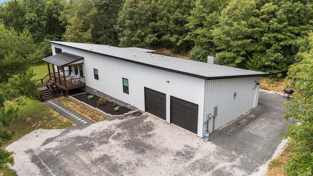 2006 Goodrich Rd, Nunnelly, TN 37137 - view of home's exterior featuring a garage, gravel driveway, a wooded view, a wooden deck, and a chimney