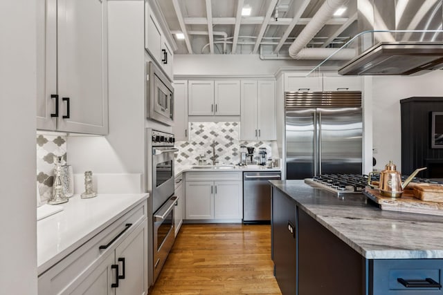 320 Liberty Pike Unit 205, Franklin, TN 37064 - kitchen featuring built in appliances, backsplash, light wood-style floors, white cabinets, and light stone countertops