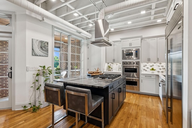 320 Liberty Pike Unit 205, Franklin, TN 37064 - kitchen with built in appliances, island range hood, light wood-type flooring, and backsplash