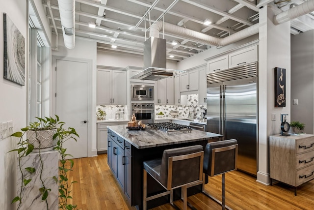 320 Liberty Pike Unit 205, Franklin, TN 37064 - kitchen featuring built in appliances, island range hood, a center island, light wood-style floors, and white cabinetry