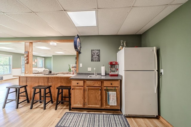 3205 Rocky Point Ln, Stewart, TN 37175 - kitchen with freestanding refrigerator, a paneled ceiling, light wood-type flooring, dark countertops, and brown cabinetry
