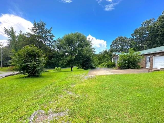 104 Tobaccoport Dock Rd, Bumpus Mills, TN 37028 - view of green lawn featuring asphalt driveway and a garage