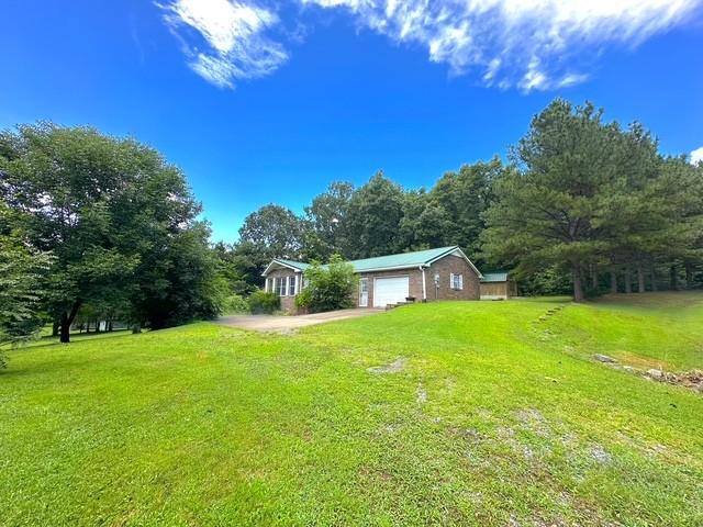 104 Tobaccoport Dock Rd, Bumpus Mills, TN 37028 - view of green lawn featuring driveway and a garage
