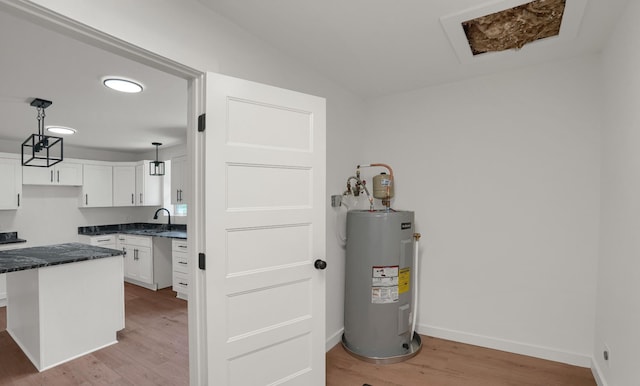 306 Forrest St, Watertown, TN 37184 - kitchen with water heater, light wood-style flooring, white cabinets, pendant lighting, and dark stone counters