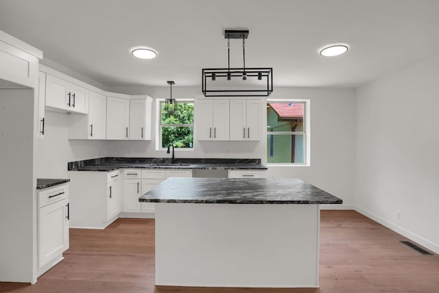 306 Forrest St, Watertown, TN 37184 - kitchen with white cabinets, light wood-style flooring, a center island, and hanging light fixtures
