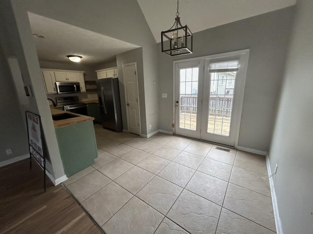 3421 Foxrun Ln, Clarksville, TN 37042 - kitchen with appliances with stainless steel finishes, white cabinets, a chandelier, pendant lighting, and light tile patterned floors