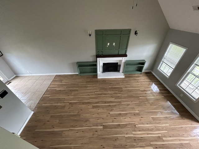 3421 Foxrun Ln, Clarksville, TN 37042 - unfurnished living room featuring wood finished floors, high vaulted ceiling, and a fireplace with raised hearth