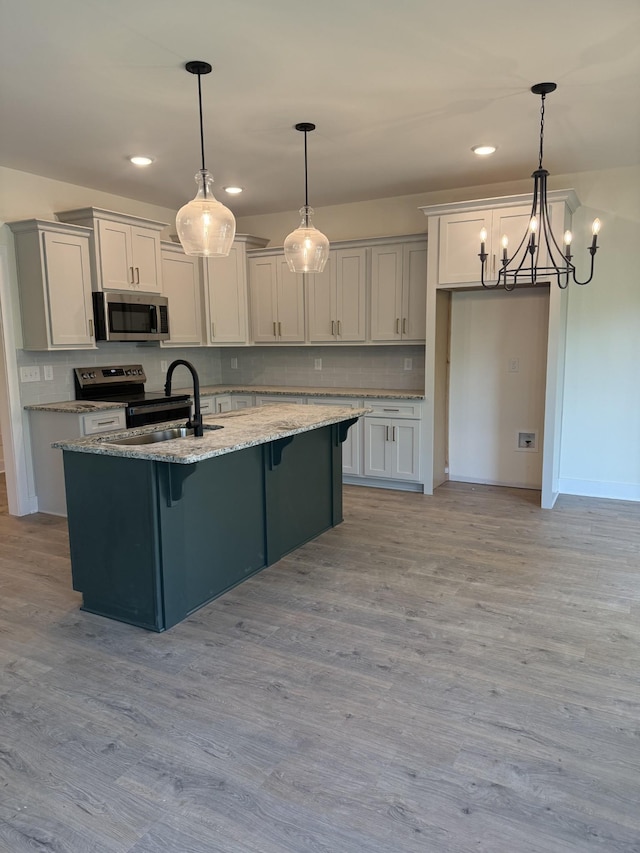 317 Wesson Dr, Clarksville, TN 37043 - kitchen with appliances with stainless steel finishes, backsplash, a center island with sink, a chandelier, and recessed lighting