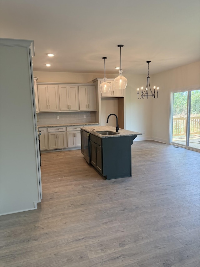 317 Wesson Dr, Clarksville, TN 37043 - kitchen featuring a kitchen island with sink, light wood-type flooring, tasteful backsplash, light stone counters, and pendant lighting