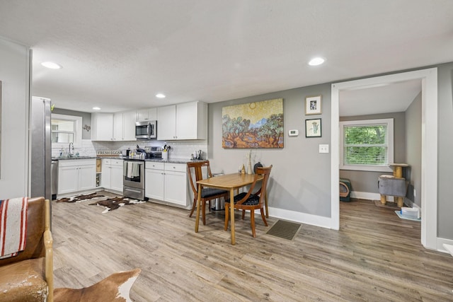 813 Lonnie St, Columbia, TN 38401 - kitchen with stainless steel appliances, light wood-style flooring, white cabinetry, recessed lighting, and decorative backsplash