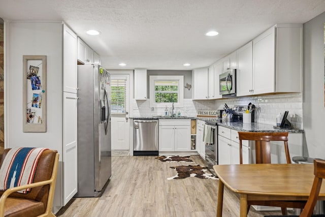 813 Lonnie St, Columbia, TN 38401 - kitchen featuring stainless steel appliances, light wood finished floors, white cabinets, backsplash, and a textured ceiling