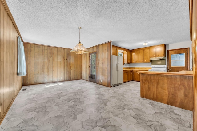 207 Short St, Clarksville, TN 37042 - kitchen with freestanding refrigerator, stove, brown cabinetry, wooden walls, and under cabinet range hood