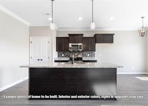 918 Vendue Ave, Clarksville, TN 37042 - kitchen with stainless steel microwave, crown molding, an island with sink, dark brown cabinetry, and dark wood-style flooring