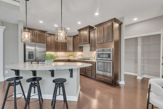 412 Warren Hill Dr, Mount Juliet, TN 37122 - kitchen with appliances with stainless steel finishes, tasteful backsplash, light stone countertops, dark brown cabinetry, and a breakfast bar area