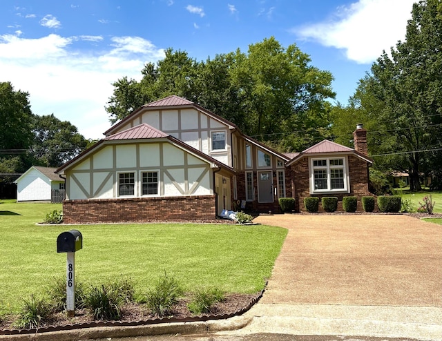 806 Sharon Cir, Lawrenceburg, TN 38464 - tudor house featuring a chimney, brick siding, a front yard, and concrete driveway