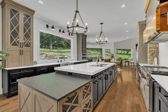 3120 Boxley View Ln, Franklin, TN 37064 - kitchen featuring a chandelier, stainless steel stove, a center island with sink, custom exhaust hood, and light wood-type flooring