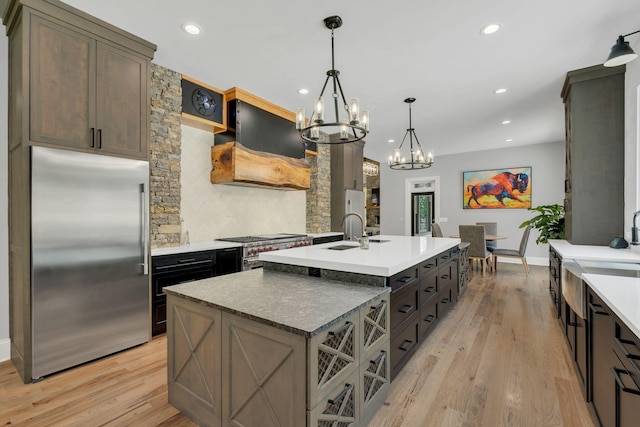 3120 Boxley View Ln, Franklin, TN 37064 - kitchen with appliances with stainless steel finishes, ventilation hood, a chandelier, an island with sink, and light wood-style flooring