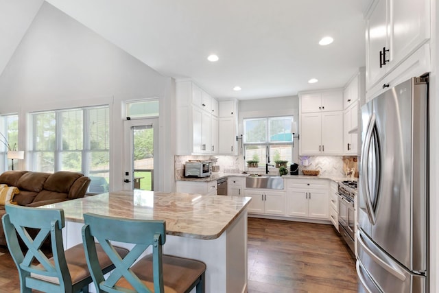 332 Country Club Rd, Winchester, TN 37398 - kitchen with stainless steel appliances, decorative backsplash, light stone countertops, white cabinets, and a breakfast bar area