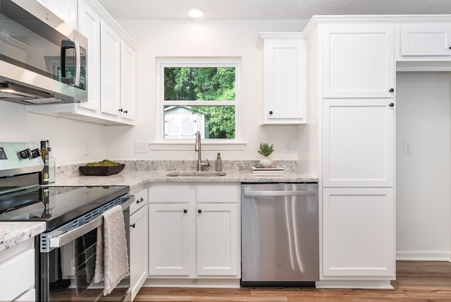 1204 Lambeth Way, Antioch, TN 37013 - kitchen with stainless steel appliances, white cabinetry, light stone counters, and light wood-type flooring