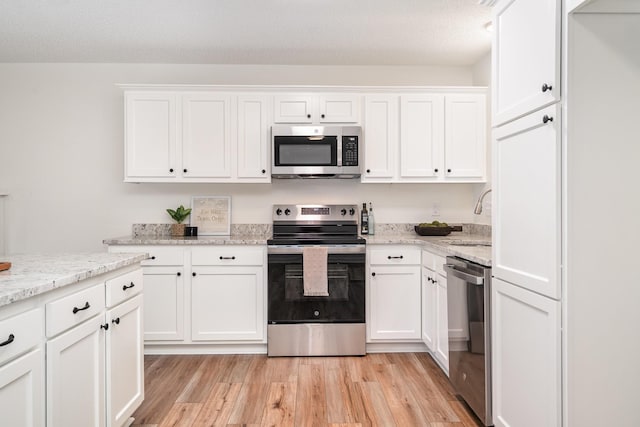 1204 Lambeth Way, Antioch, TN 37013 - kitchen with stainless steel appliances, white cabinets, light wood-style floors, and light stone counters