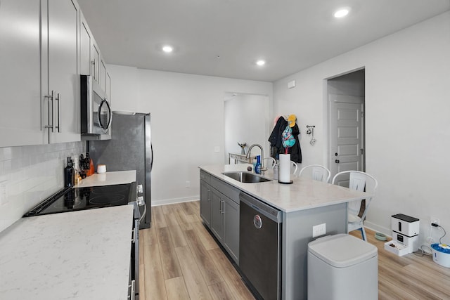 622 Birdie Dr, Spring Hill, TN 37174 - kitchen with appliances with stainless steel finishes, an island with sink, light wood-type flooring, decorative backsplash, and recessed lighting