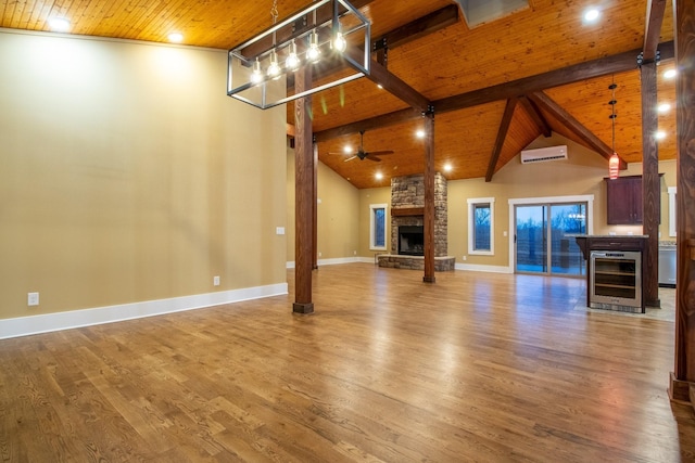 1224 Hangar Dr, Springfield, TN 37172 - unfurnished living room with wine cooler, an AC wall unit, a wooden ceiling with exposed beams, a stone fireplace, and wood finished floors