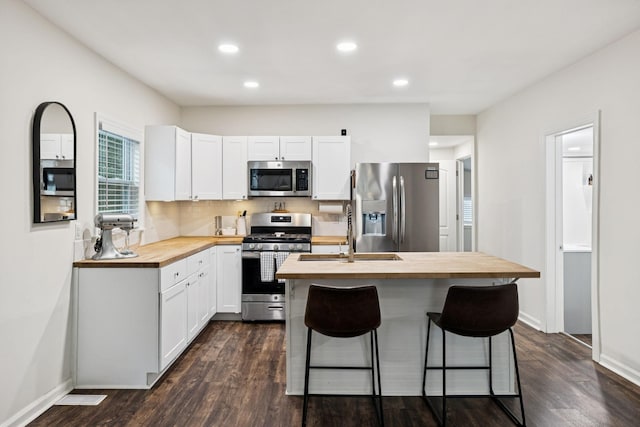 819 Woodside St, Columbia, TN 38401 - kitchen with butcher block countertops, appliances with stainless steel finishes, dark wood-type flooring, white cabinets, and a center island with sink