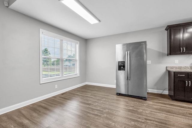 626 Snowshoe Ln, Clarksville, TN 37040 - kitchen with stainless steel fridge, dark brown cabinets, wood finished floors, and light stone counters