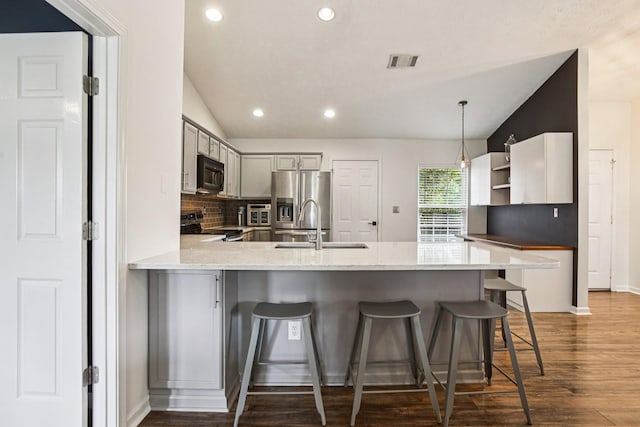 3315 Monoco Dr, Spring Hill, TN 37174 - kitchen with stainless steel appliances, a peninsula, vaulted ceiling, dark wood-style floors, and recessed lighting