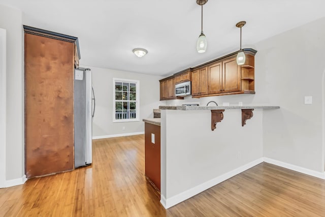 3190 Marthas Chapel Rd, Cunningham, TN 37052 - kitchen featuring appliances with stainless steel finishes, open shelves, light wood-style flooring, a kitchen breakfast bar, and light countertops