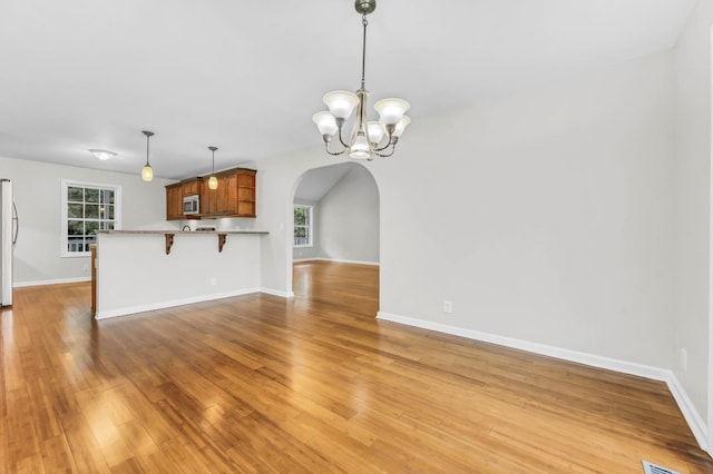 3190 Marthas Chapel Rd, Cunningham, TN 37052 - unfurnished living room featuring arched walkways, a chandelier, and light wood-style floors