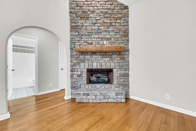 3190 Marthas Chapel Rd, Cunningham, TN 37052 - unfurnished living room with wood finished floors, a stone fireplace, vaulted ceiling, and arched walkways