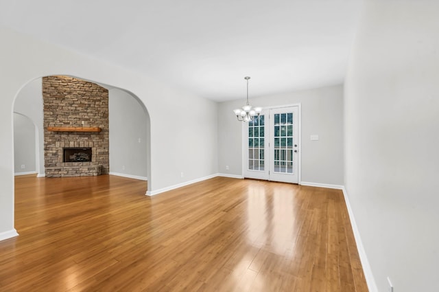 3190 Marthas Chapel Rd, Cunningham, TN 37052 - unfurnished living room featuring a chandelier, light wood finished floors, a fireplace, and arched walkways