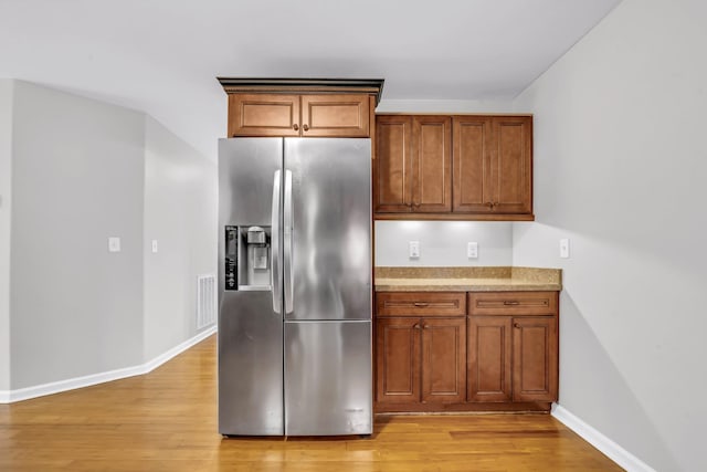 3190 Marthas Chapel Rd, Cunningham, TN 37052 - kitchen featuring stainless steel fridge with ice dispenser, light wood finished floors, brown cabinets, and light stone countertops