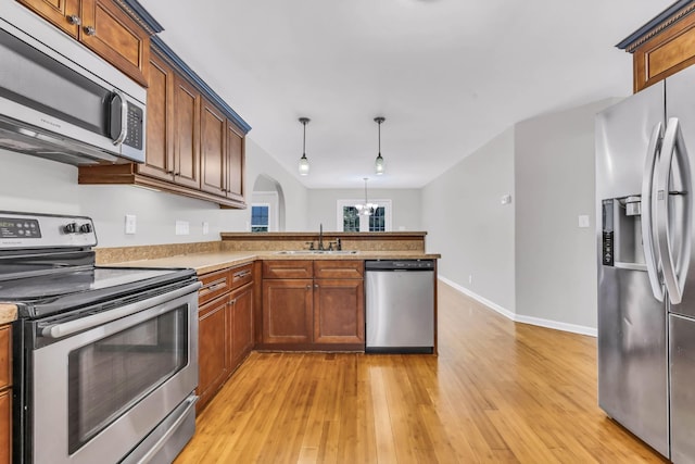 3190 Marthas Chapel Rd, Cunningham, TN 37052 - kitchen featuring stainless steel appliances, light wood finished floors, a peninsula, light countertops, and arched walkways
