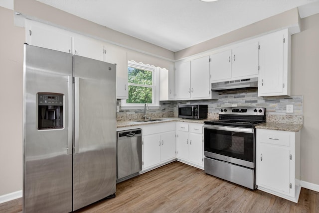 609 Chrisman Dr, Clarksville, TN 37042 - kitchen featuring stainless steel appliances, under cabinet range hood, white cabinetry, light wood-style floors, and decorative backsplash