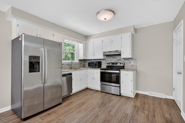 609 Chrisman Dr, Clarksville, TN 37042 - kitchen featuring stainless steel appliances, under cabinet range hood, light wood-type flooring, white cabinets, and backsplash