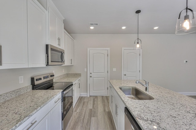 1753 Flora Grv, Hermitage, TN 37076 - kitchen featuring appliances with stainless steel finishes, light wood finished floors, white cabinetry, light stone countertops, and decorative light fixtures