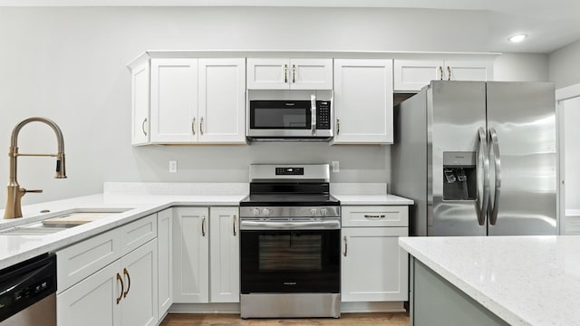 570 Main St S, Ashland City, TN 37015 - kitchen with stainless steel appliances, white cabinets, light stone countertops, light wood-style floors, and recessed lighting
