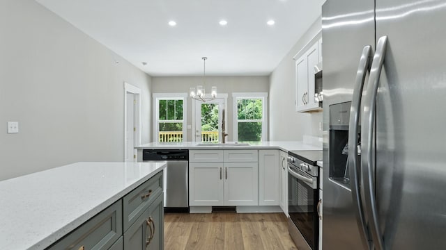 570 Main St S, Ashland City, TN 37015 - kitchen featuring appliances with stainless steel finishes, recessed lighting, light wood finished floors, a peninsula, and a chandelier