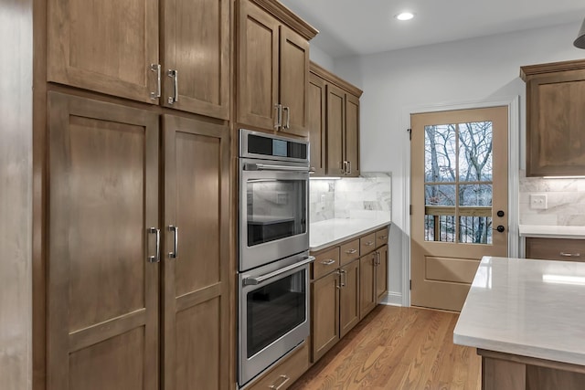 418 Stonemeadow Rd, Clarksville, TN 37043 - kitchen with stainless steel double oven, light countertops, light wood finished floors, decorative backsplash, and recessed lighting