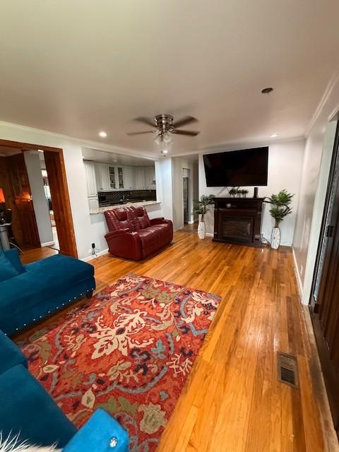 102 Thorogood St, Cowan, TN 37318 - living area featuring wood finished floors, a ceiling fan, ornamental molding, a fireplace, and recessed lighting