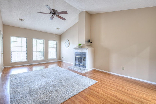 302 Laurel Hill Dr, Old Hickory, TN 37138 - unfurnished living room featuring light wood-type flooring, ceiling fan, a textured ceiling, a glass covered fireplace, and high vaulted ceiling